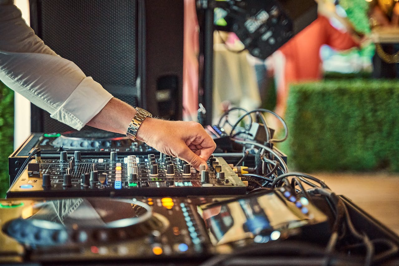 Close-up of DJ adjusting an audio mixer outdoors, showcasing modern music equipment.