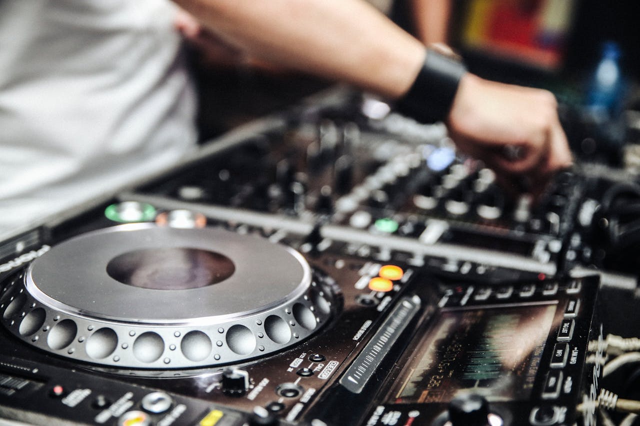 DJ hands adjusting mixer controls in an energetic night party setting.