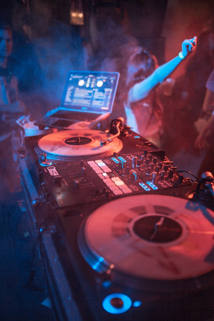 Colorful DJ setup with vinyl turntables and active party crowd at night.